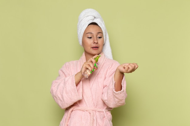 Mujer en bata de baño rosa con spray