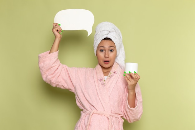 Foto gratuita mujer en bata de baño rosa con tarjeta blanca y crema