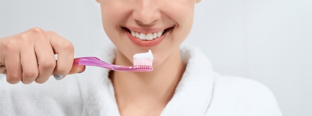 Mujer en bata blanca con cepillo de dientes con pasta