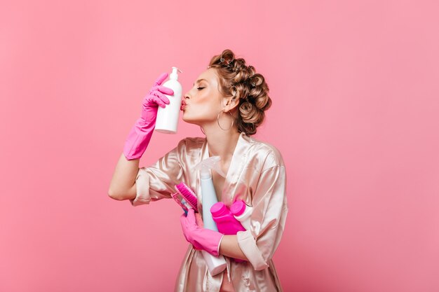 Mujer en bata de seda y rizadores de pelo besos detergente lavavajillas