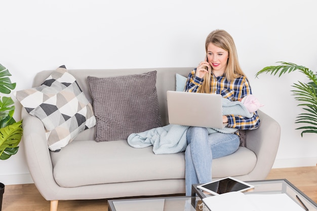 Mujer con bebé hablando por teléfono y usando laptop