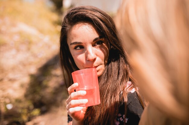 Mujer con bebida mirando amigo