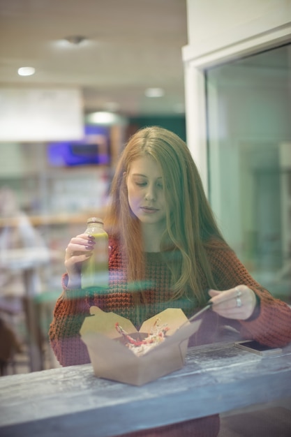 Foto gratuita mujer con bebida saludable comiendo ensalada