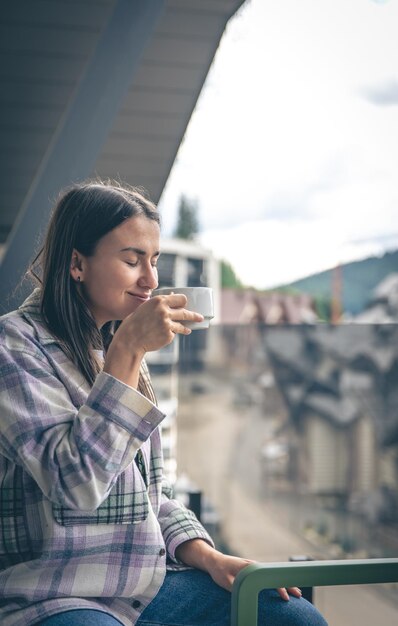 Una mujer bebiendo café en el balcón por la mañana.