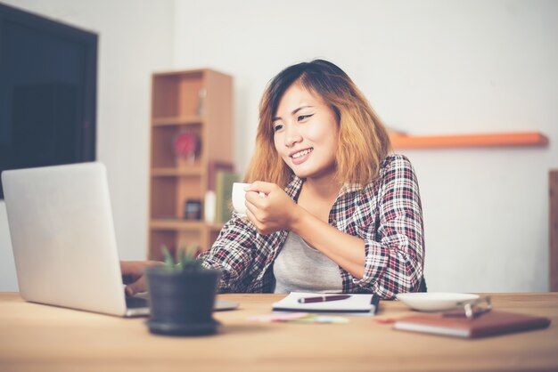 una mujer bebiendo café junto al ordenador