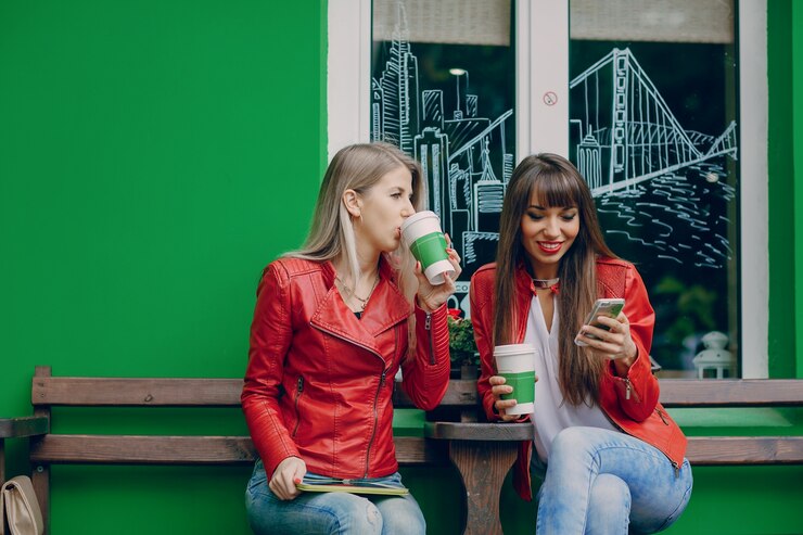 Foto gratuito mujer bebiendo café y otra mirando su móvil