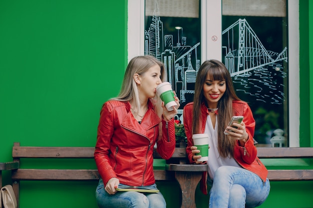 Mujer bebiendo café y otra mirando su móvil