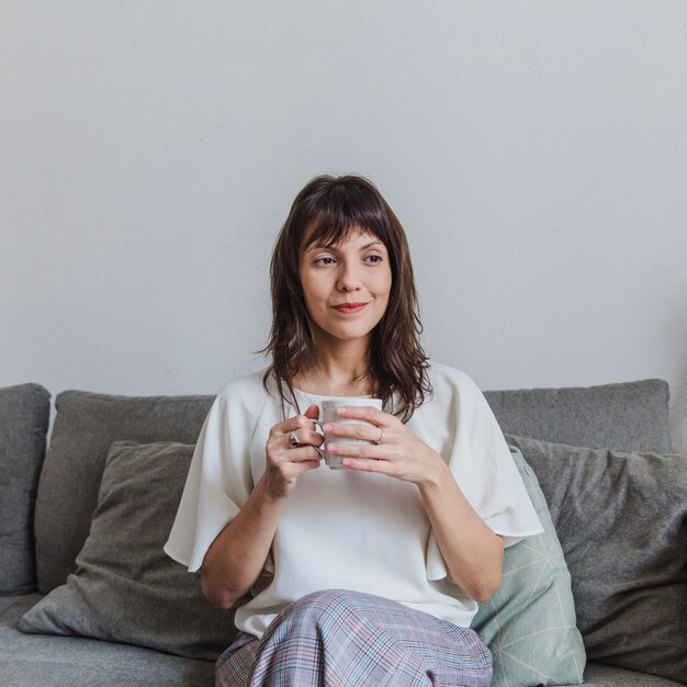 Mujer bebiendo café en sofá