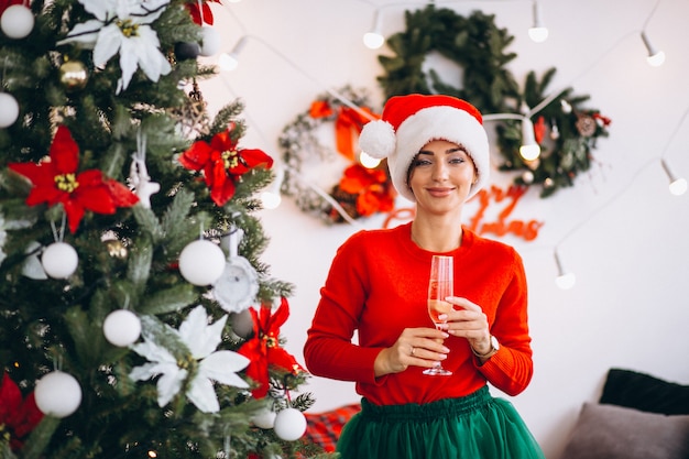 Mujer bebiendo champaigne por arbol de navidad