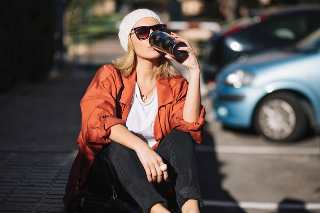 Mujer bebiendo en el estacionamiento