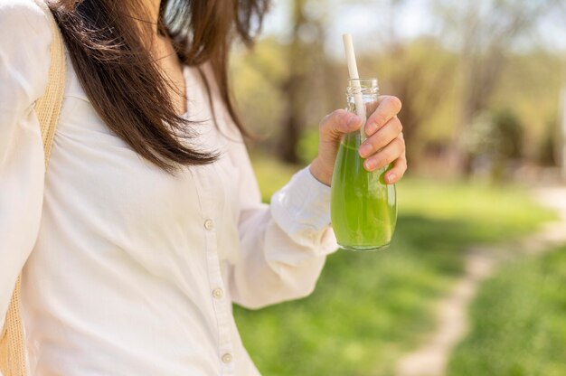 Mujer bebiendo jugo de botella de vidrio