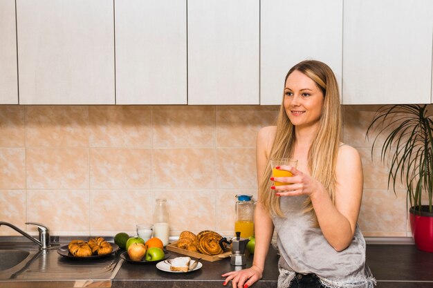 Mujer bebiendo jugo en la cocina