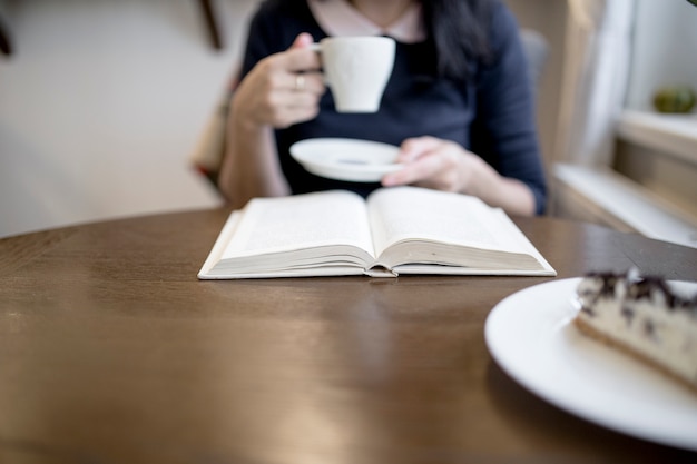 Mujer bebiendo y leyendo el libro en el café