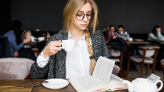 Foto gratuita mujer bebiendo y leyendo el libro