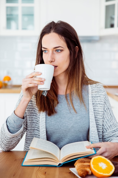 Mujer bebiendo mientras lee el libro