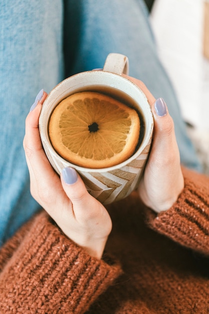 Mujer bebiendo una taza de té de hierbas de naranja caliente