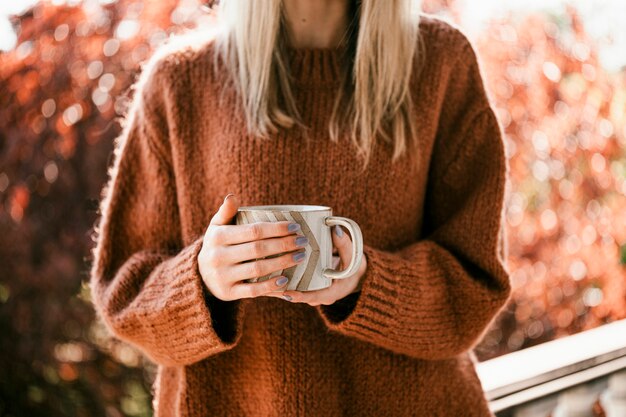 Mujer bebiendo una taza de té de hierbas de naranja caliente