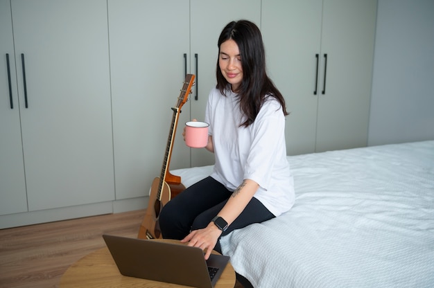 Mujer bebiendo té y usando laptop en casa durante la cuarentena