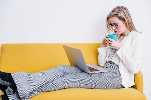 Mujer bebiendo y usando la computadora portátil