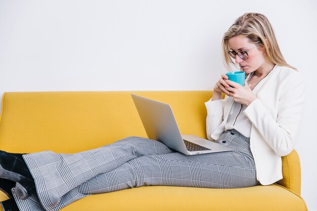 Mujer bebiendo y usando la computadora portátil