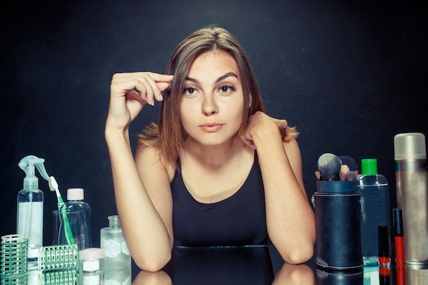 Foto gratuita mujer de belleza aplicando maquillaje. hermosa chica mirando en el espejo y aplicando cosmético con un pincel grande.