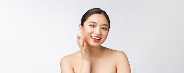 Mujer de belleza para el cuidado de la piel Mujer de belleza sonriendo aplicando crema Retrato de belleza de una hermosa modelo femenina caucásica asiática aislada en blanco