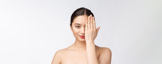 Mujer de belleza para el cuidado de la piel Mujer de belleza sonriendo aplicando crema Retrato de belleza de una hermosa modelo femenina caucásica asiática aislada en blanco