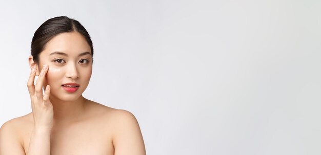 Mujer de belleza para el cuidado de la piel Mujer de belleza sonriendo aplicando crema Retrato de belleza de una hermosa modelo femenina caucásica asiática aislada en blanco