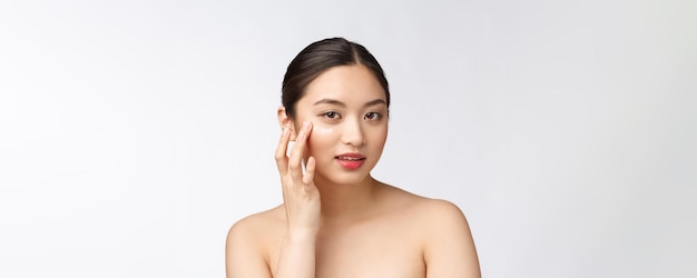 Mujer de belleza para el cuidado de la piel Mujer de belleza sonriendo aplicando crema Retrato de belleza de una hermosa modelo femenina caucásica asiática aislada en blanco