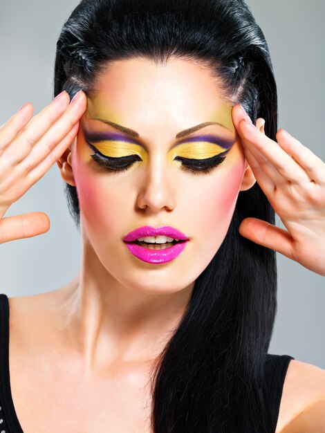 Mujer de belleza con maquillaje de moda en poses de cara