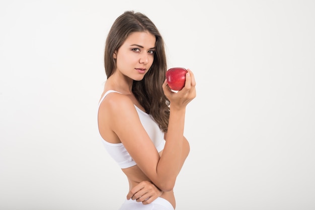Mujer de la belleza que sostiene la manzana roja mientras que está aislada en blanco