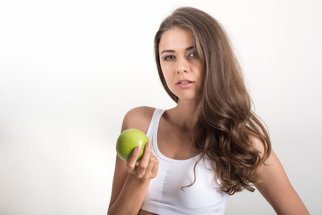 Mujer de la belleza que sostiene la manzana verde mientras que está aislada en blanco