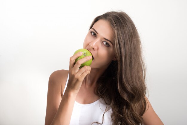 Mujer de la belleza que sostiene la manzana verde mientras que está aislada en blanco