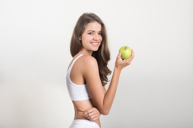 Mujer de la belleza que sostiene la manzana verde mientras que está aislada en blanco