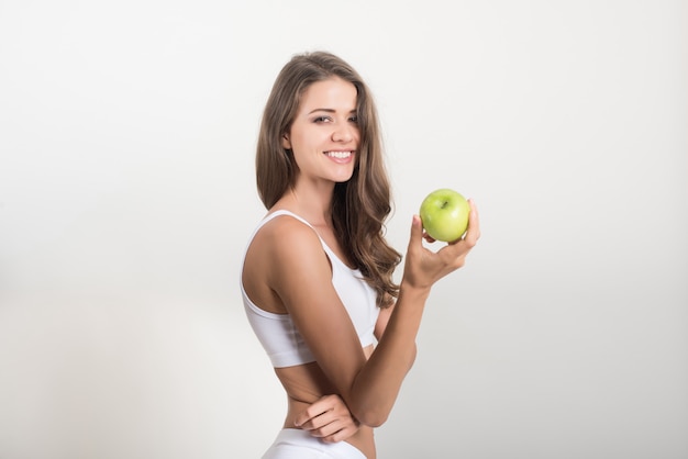 Mujer de la belleza que sostiene la manzana verde mientras que está aislada en blanco