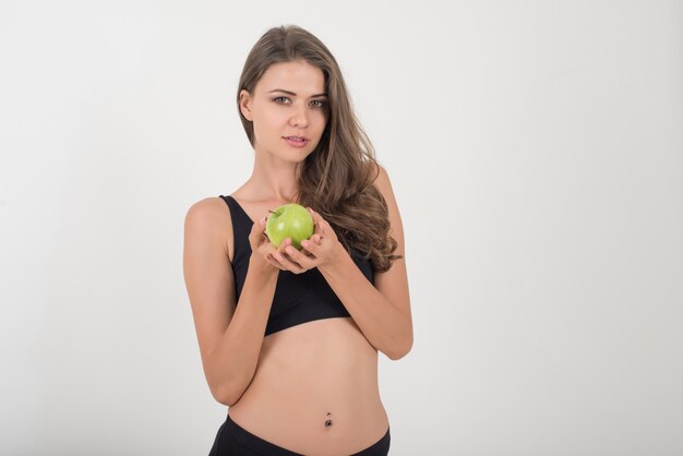 Mujer de la belleza que sostiene la manzana verde mientras que está aislada en blanco