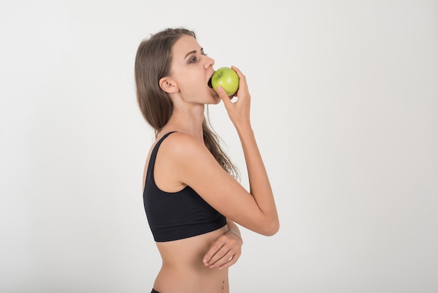 Mujer de la belleza que sostiene la manzana verde mientras que está aislada en blanco