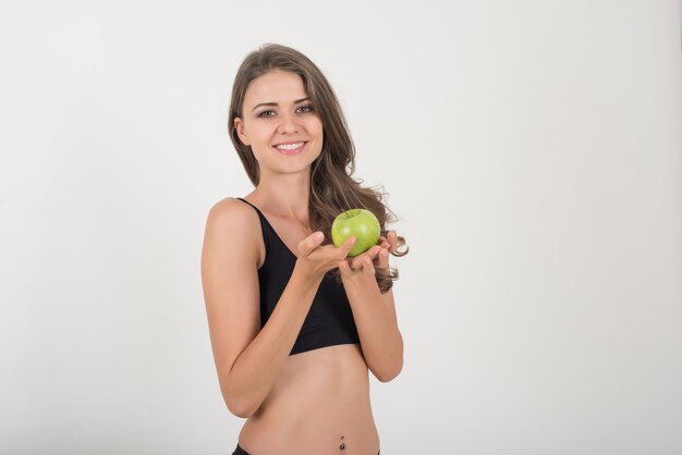 Mujer de la belleza que sostiene la manzana verde mientras que está aislada en blanco