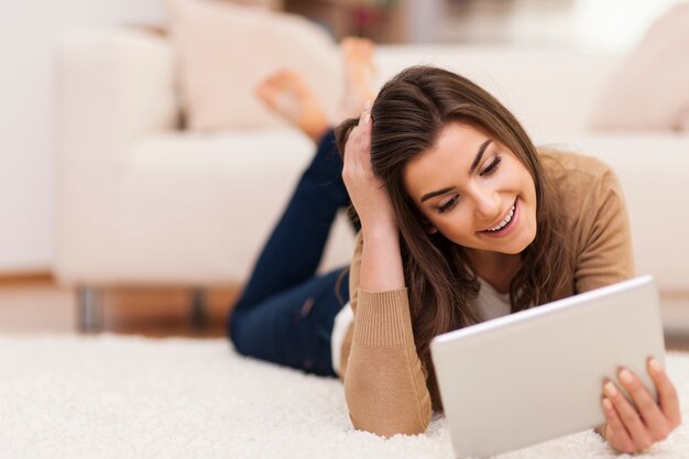 Mujer de belleza con tableta digital relajante en la alfombra