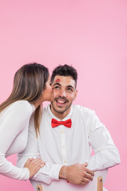 Mujer besando a un hombre feliz en la mejilla