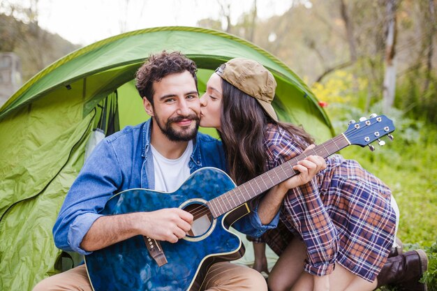 Mujer besando a hombre con guitarra