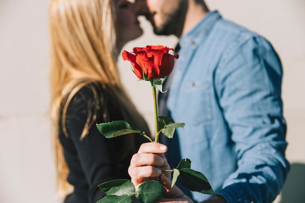 Foto gratuita mujer besándose con novio y mostrando rosa