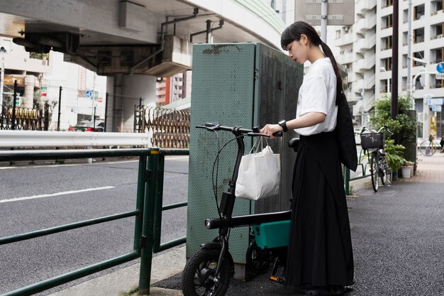 Mujer con bicicleta eléctrica en la ciudad