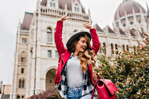 Mujer bien formada en traje de calle de moda que expresa energía y disfruta de un paseo por el casco antiguo de la ciudad