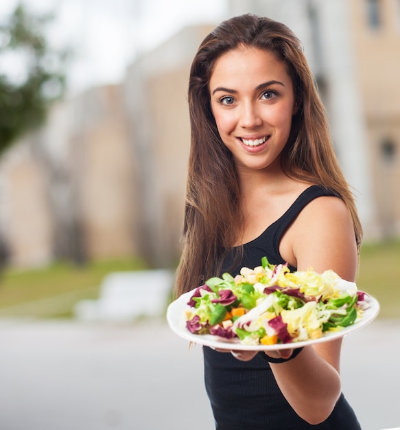 Mujer de bienvenida con un plato de ensalada