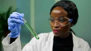 Foto gratuita mujer bióloga sosteniendo un tubo de ensayo con líquido genético examinando una muestra de adn verde