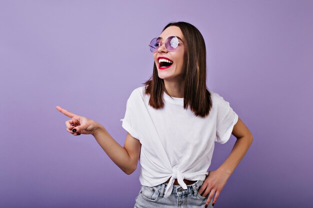 Mujer blanca inspirada en gafas de sol mirando a otro lado con risa.