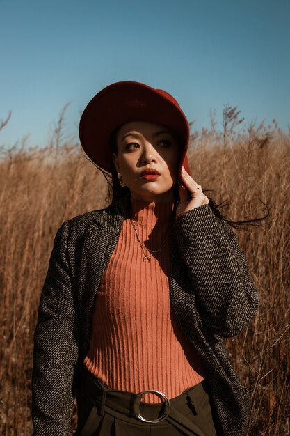 Mujer en blazer de manga larga de lunares blanco y negro y sombrero rojo en un campo