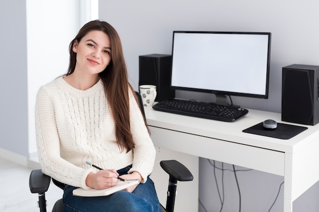 Mujer con bloc de notas en la computadora