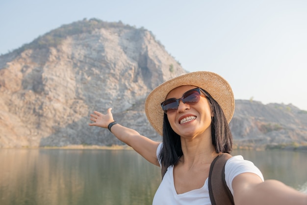 Mujer blogger mochilero asiático con smartphone tomando selfie